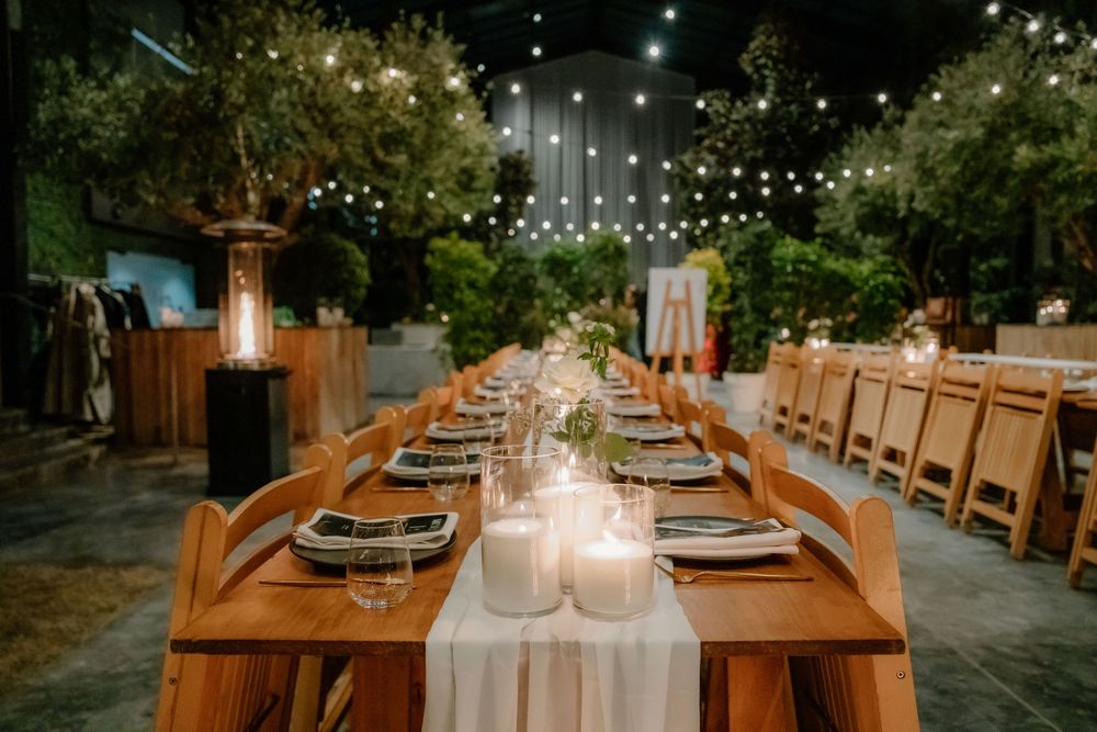 Elegant outdoor reception dining tables with wooden chairs and string lights creating a romantic atmosphere.