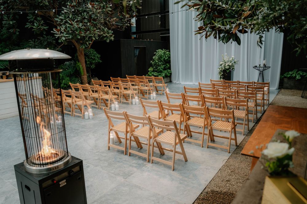 Wooden folding chairs arranged in rows for an outdoor ceremony with natural greenery backdrop.