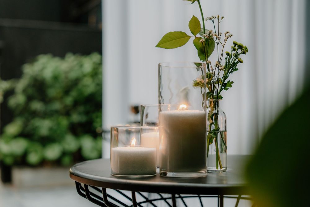 Candlelit table setting with vases holding delicate flowers and greenery in a cozy interior space.