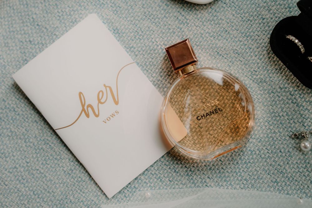 A bottle of perfume and gold 'her' text on white paper against a textured grey background.