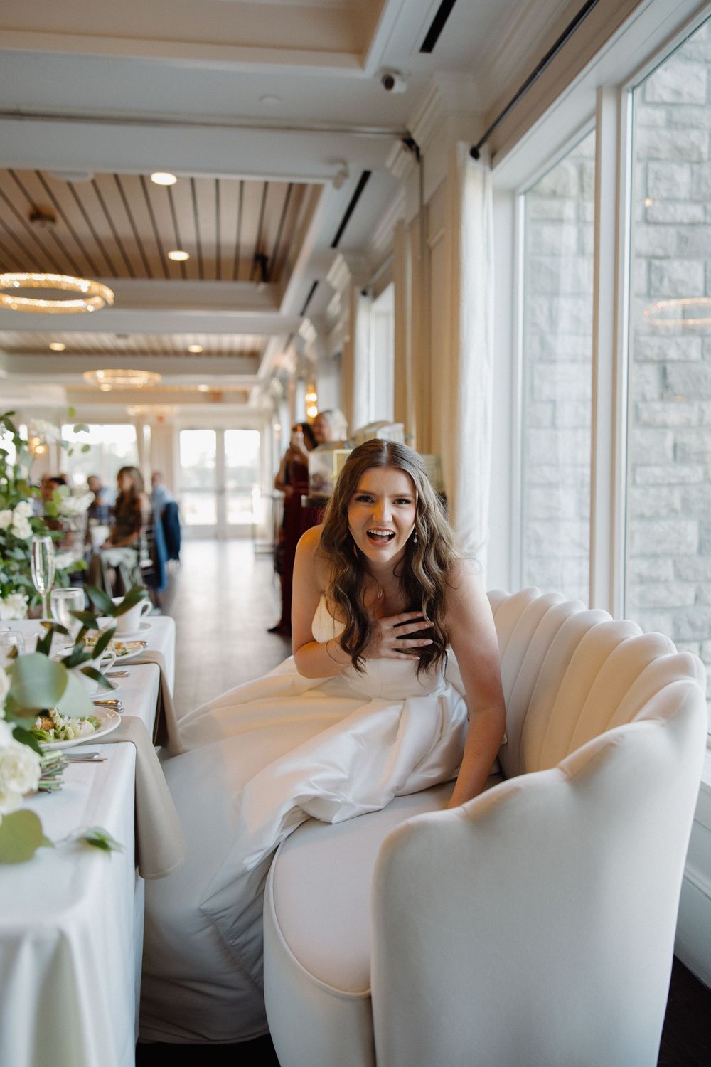 Elegant white chairs and decor in a bright, window-lit reception venue.