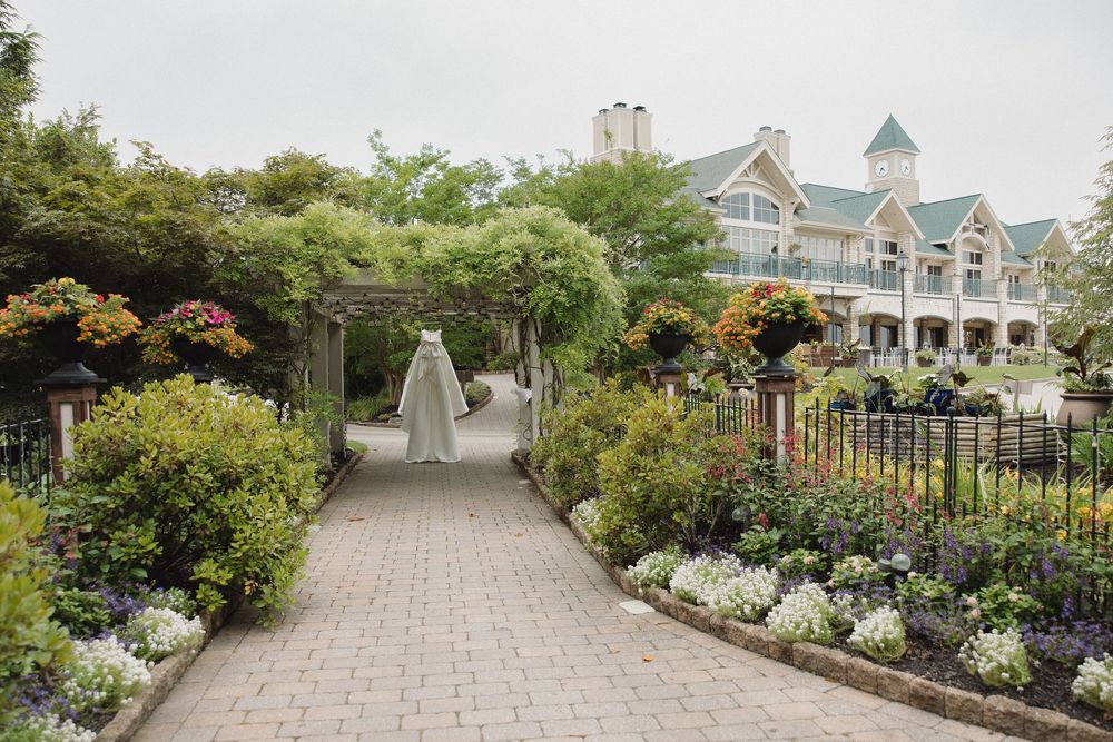 Garden pathway leads to elegant white wedding venue with landscaped flowers.