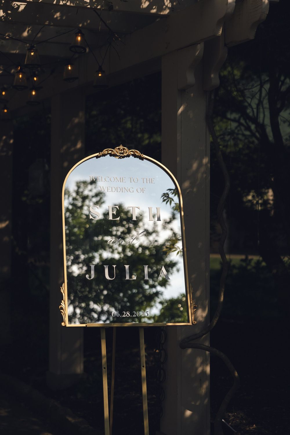 Ornate gold-framed mirror reflects outdoor wedding venue at dusk.
