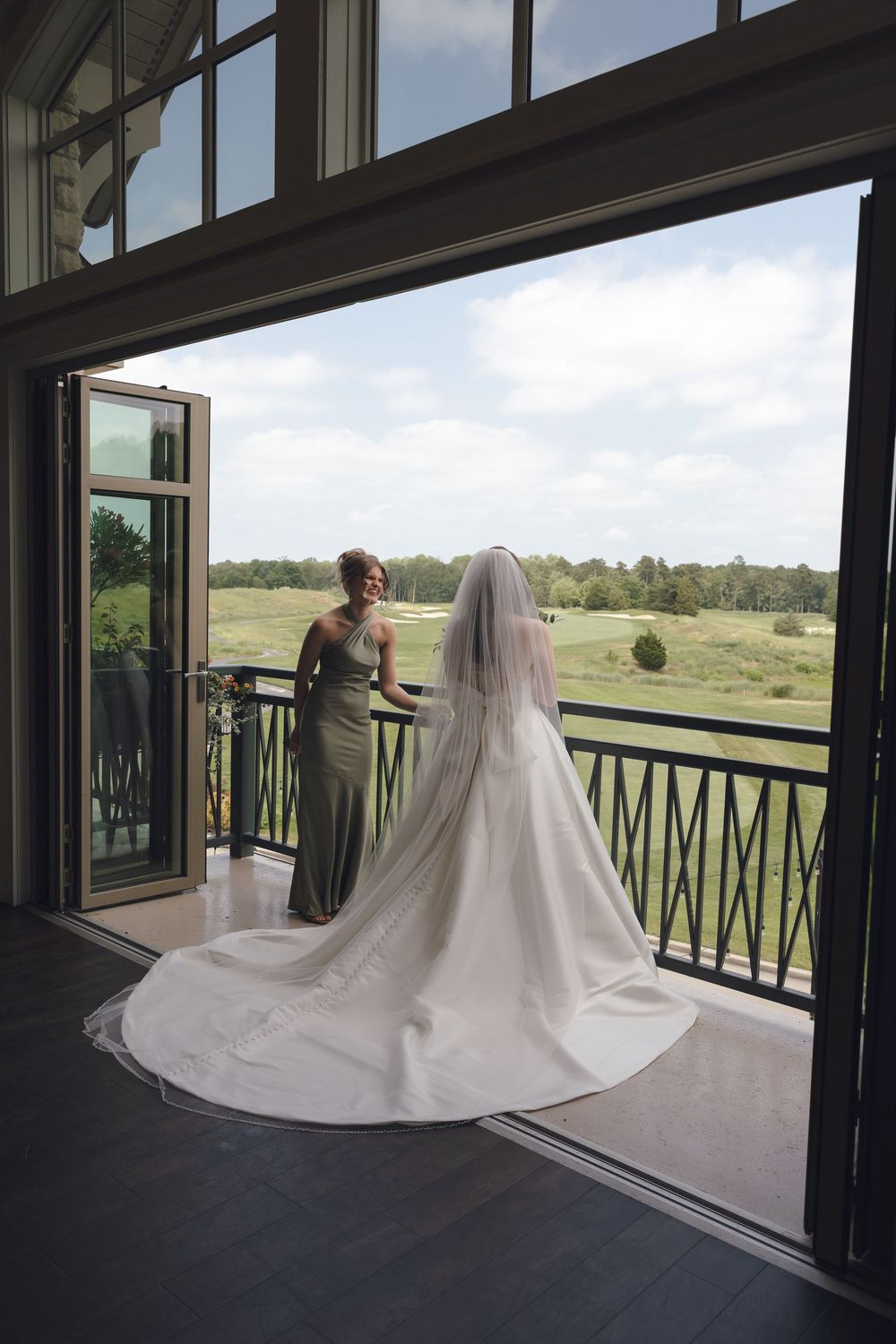 Bride's dramatic dress train flows across a covered porch with scenic views.