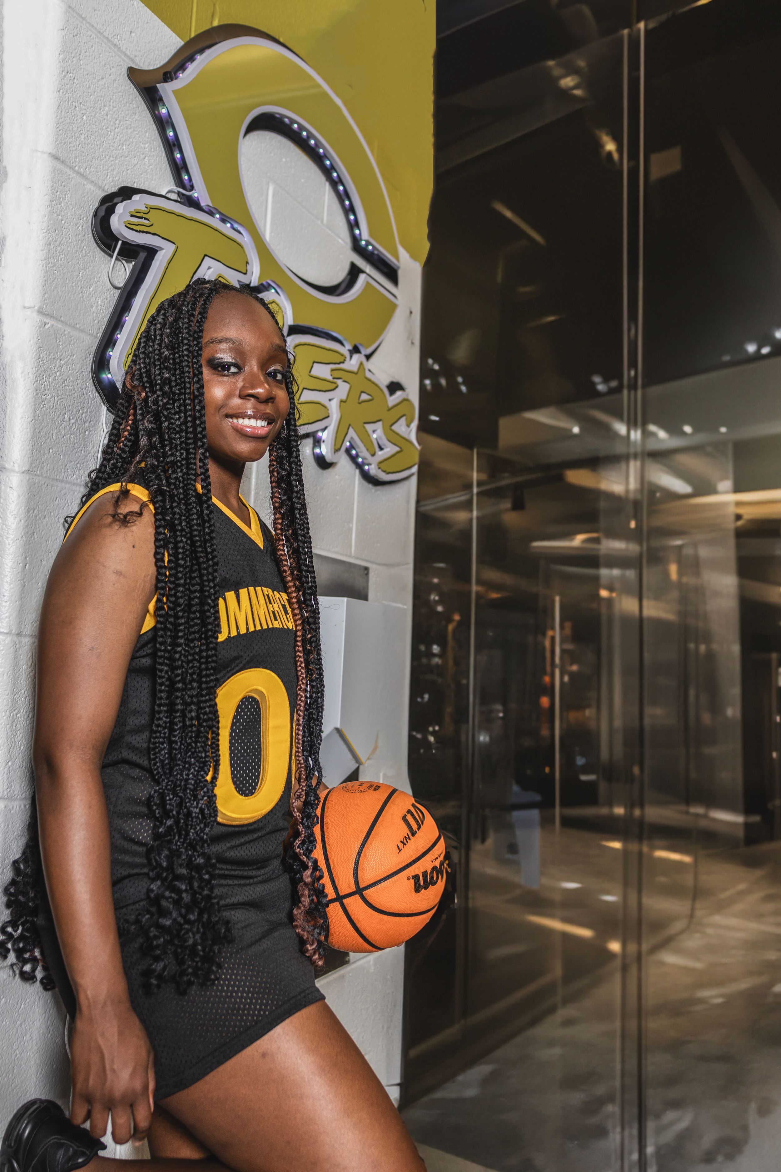 Athletic photoshoot featuring a basketball jersey against a yellow wall with sporty poses.