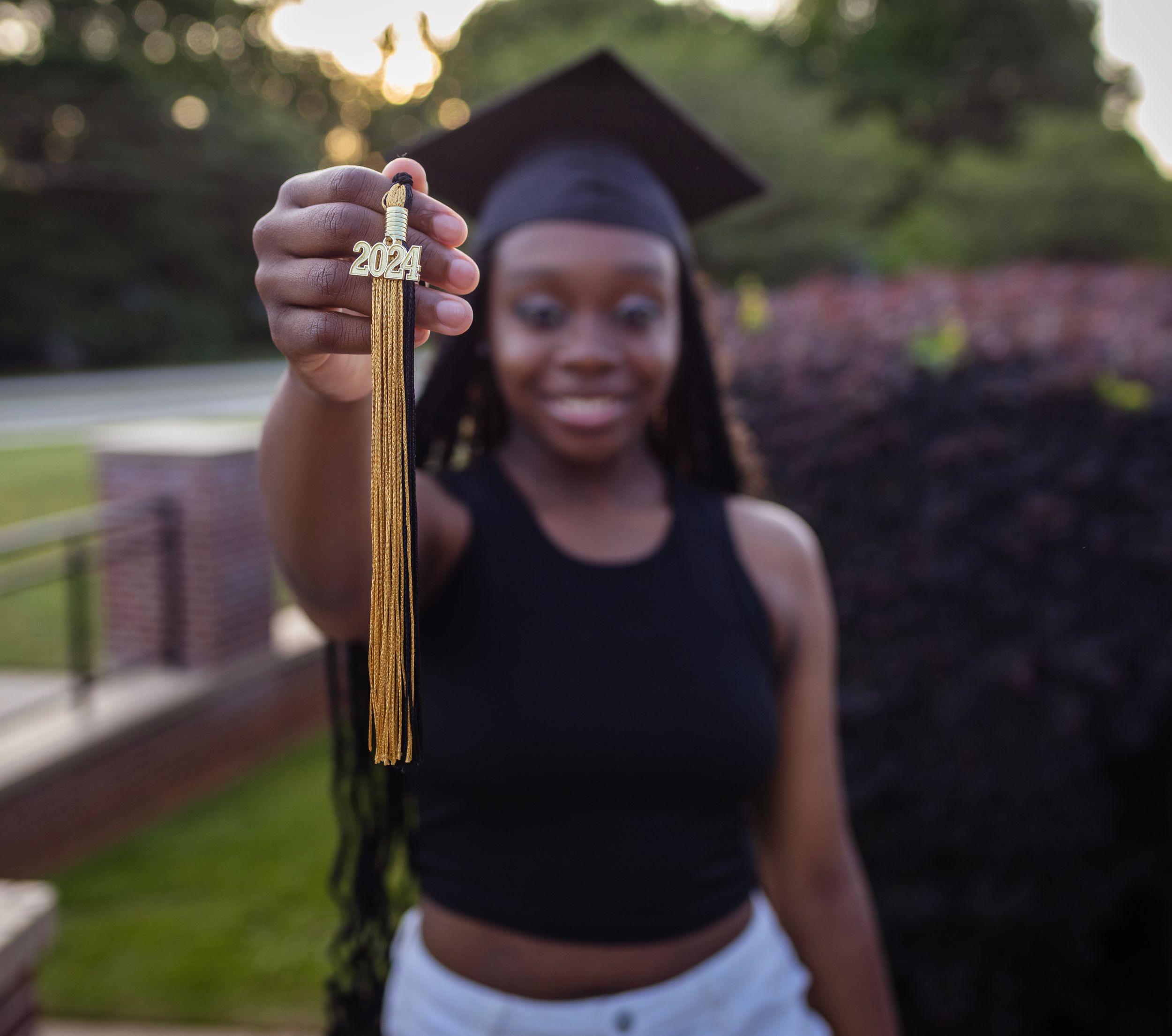 Graduation photos outdoors at sunset showing celebratory poses with a gold tassel.