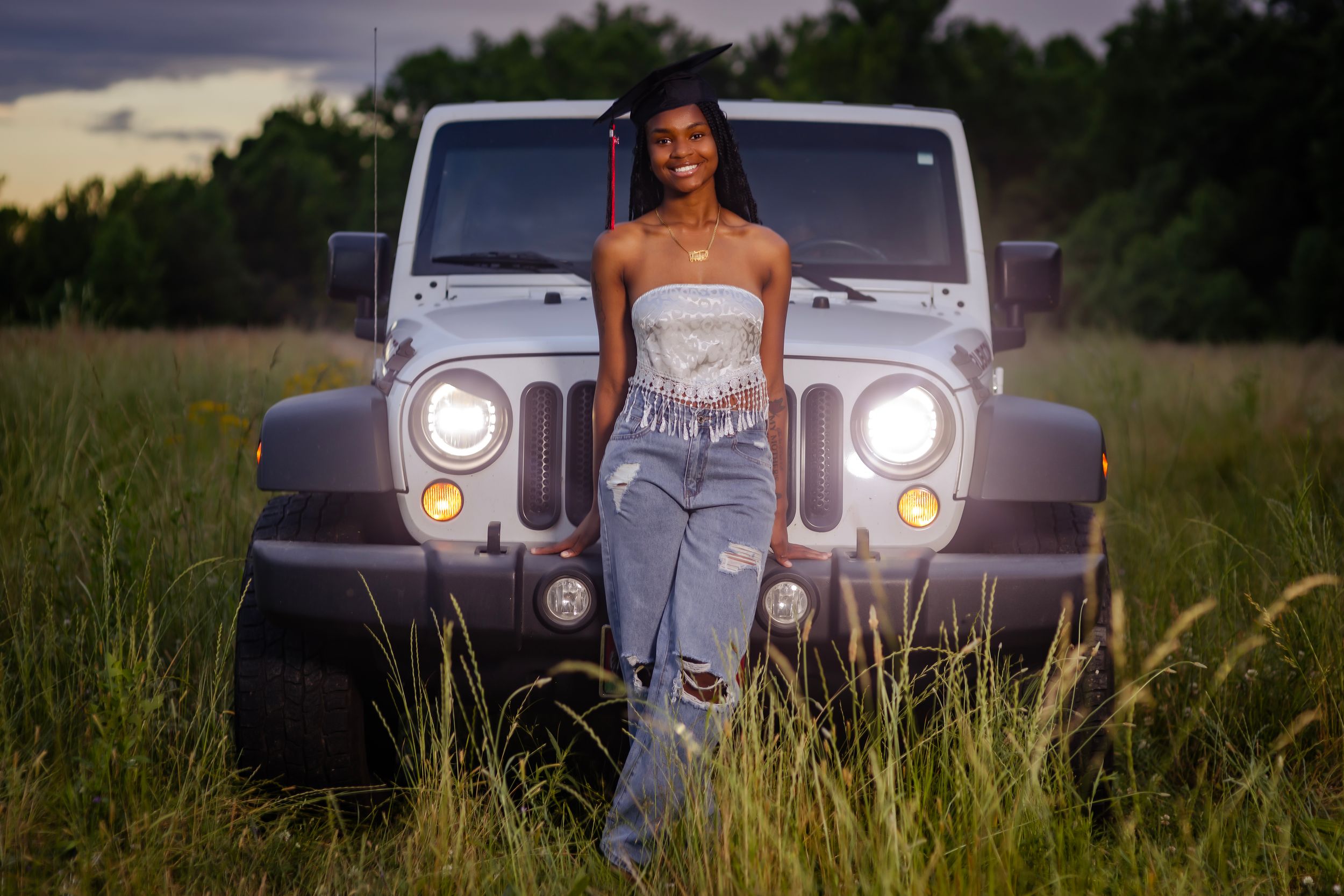 Vintage-style photo shoot with classic car in field during sunset.