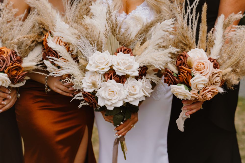Beautiful wedding bouquets with white roses, dried flowers, and pampas grass arranged in a row.
