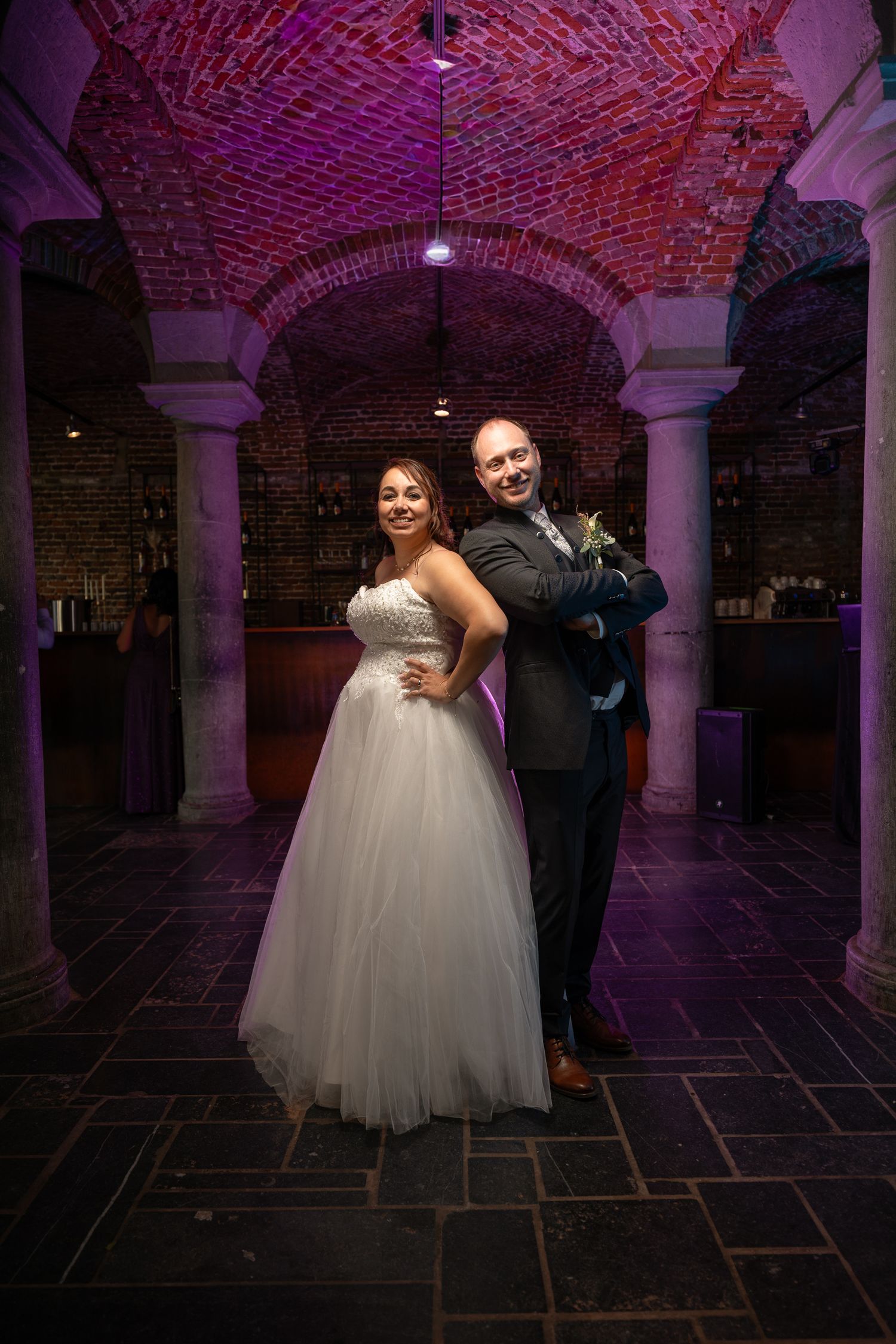 Nouvellement mariés dansent leur première danse romantique dans une salle aux murs de briques, colonnes en arche et sol en pierre,