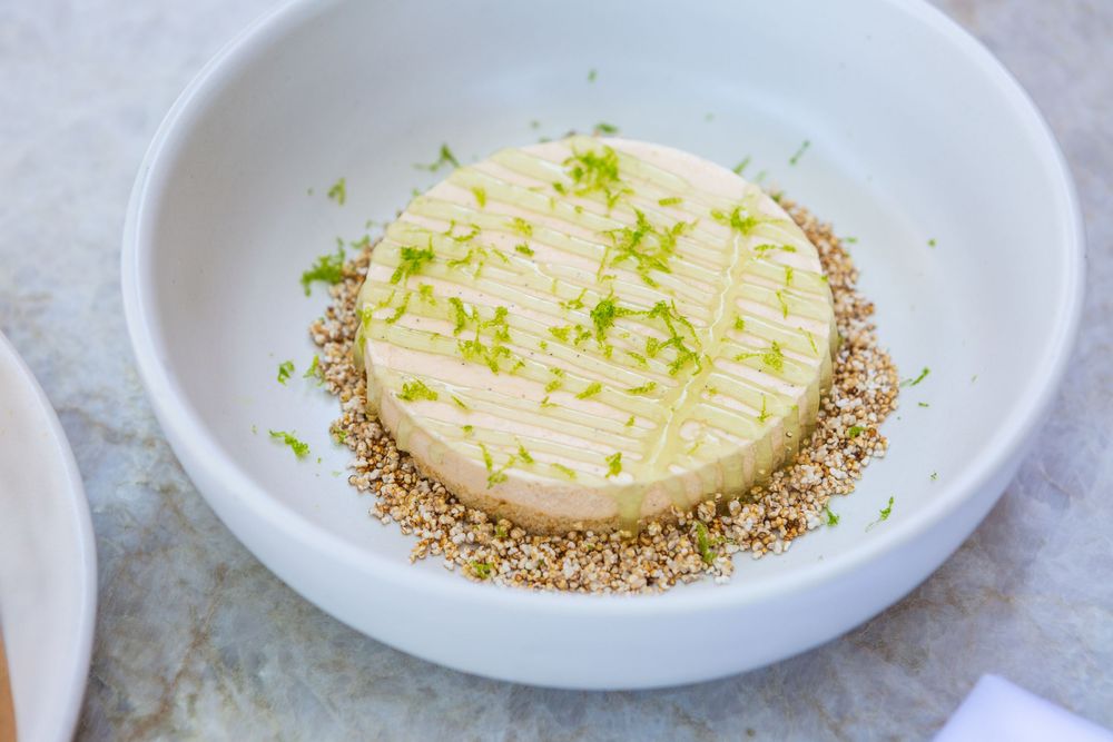 A sequence showing how to coat a goat cheese round with herbs and cracked pepper on white plates.