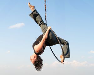 A sequence showing an acrobatic person performing a graceful aerial spin with blue sky in the background.