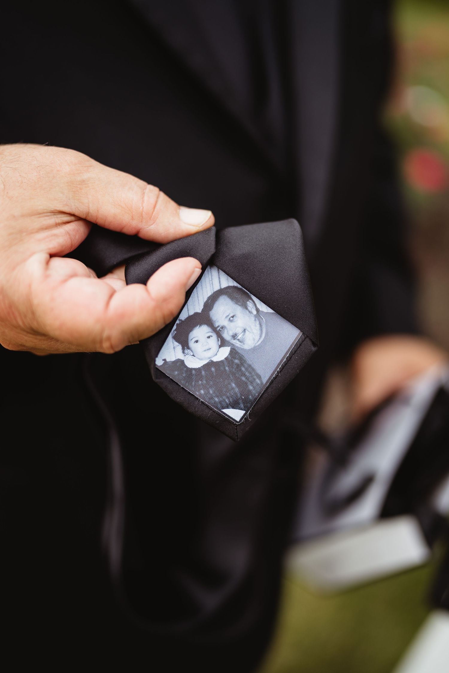 Hands holding and exchanging small black and white photographs outdoors.
