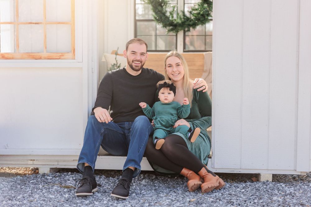 A family sitting together on steps outdoors in coordinating brown and blue casual outfits at Turkey Trac Farm in Millville NJ