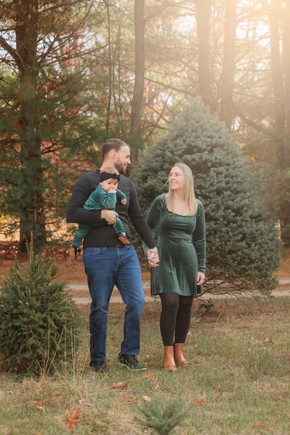 A tender photoshoot moment between two people decorating a Christmas tree farm in golden sunlightat Turkey Trac Farm in Millville NJ