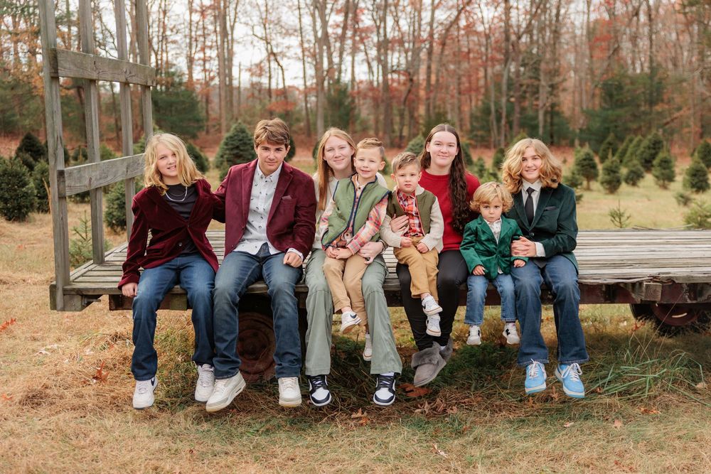 A cheerful group of friends sit together outdoors on rustic wooden steps during a photoshoot at Turkey Trac Farm in Millville NJ