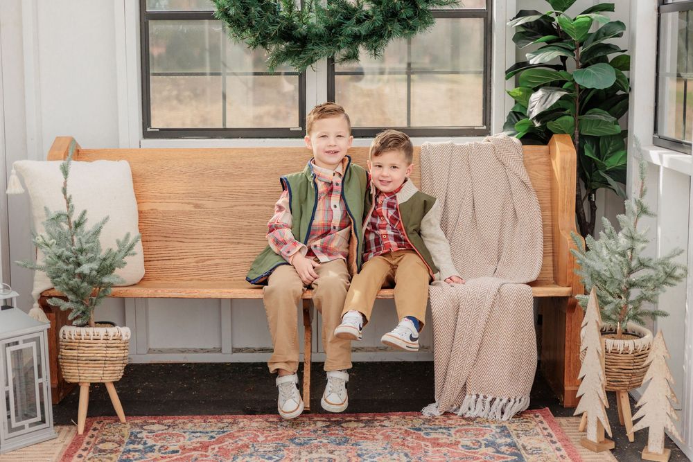 neutral-toned wooden bench sit in front of a white wall decorated with wreaths and greenery at Turkey Trac Farm in Millville NJ