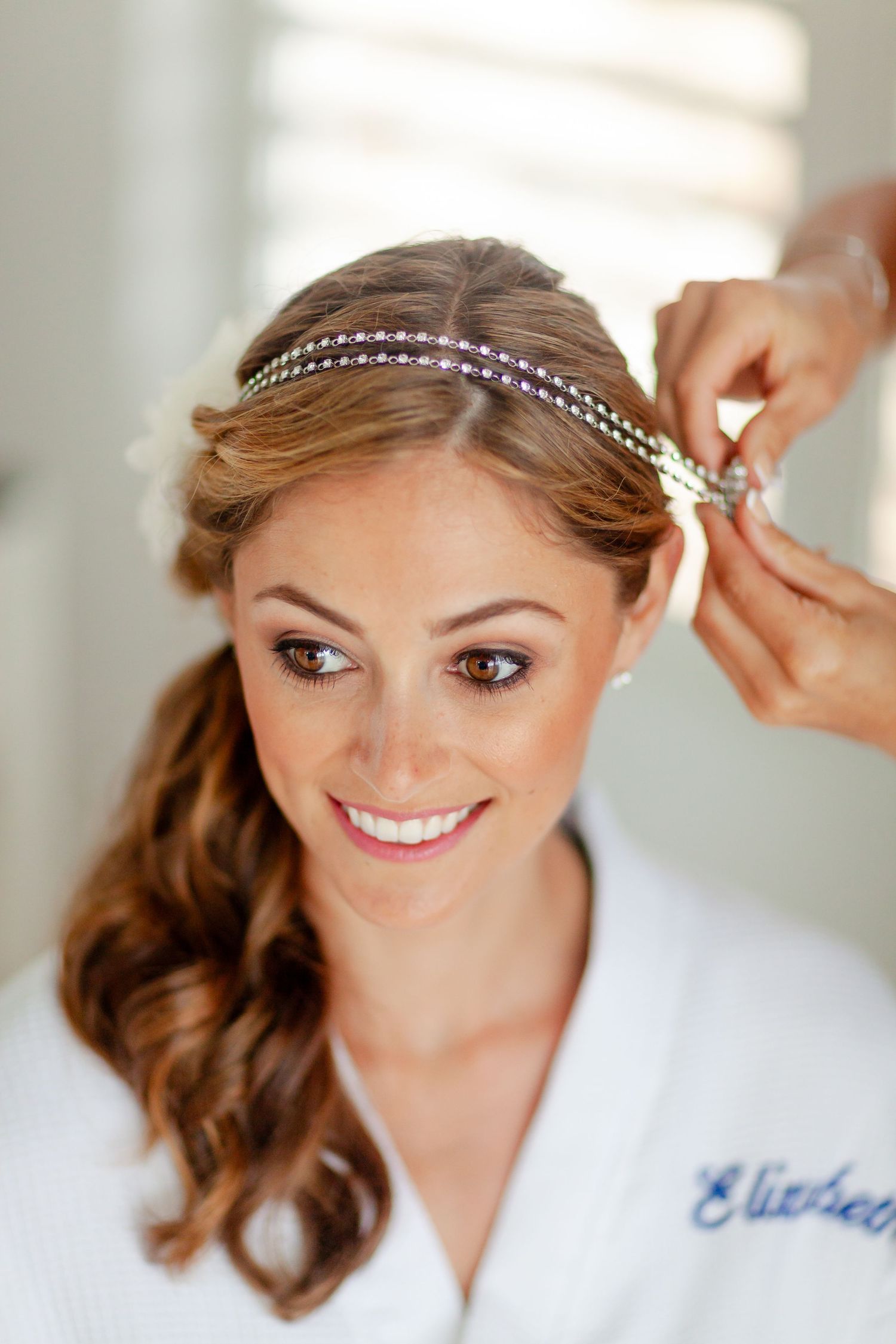 Close-up of delicate crystal headpiece being placed in styled hair.