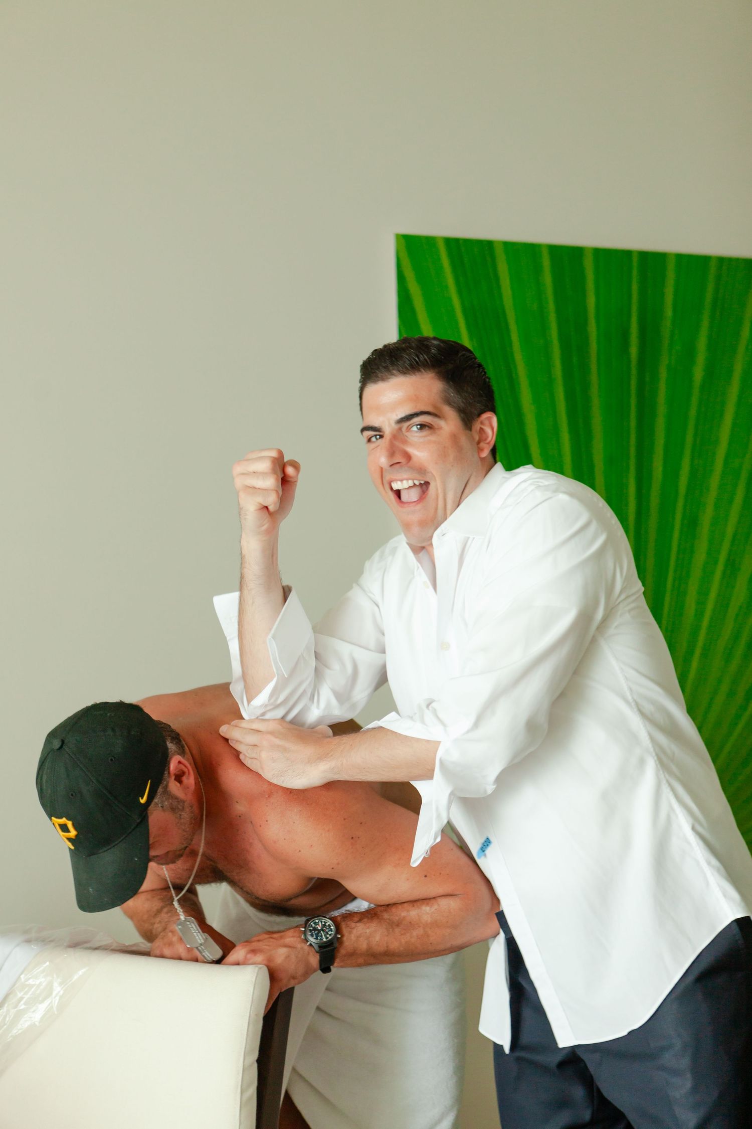 Two people sharing a playful moment during wedding preparations with one giving a massage.