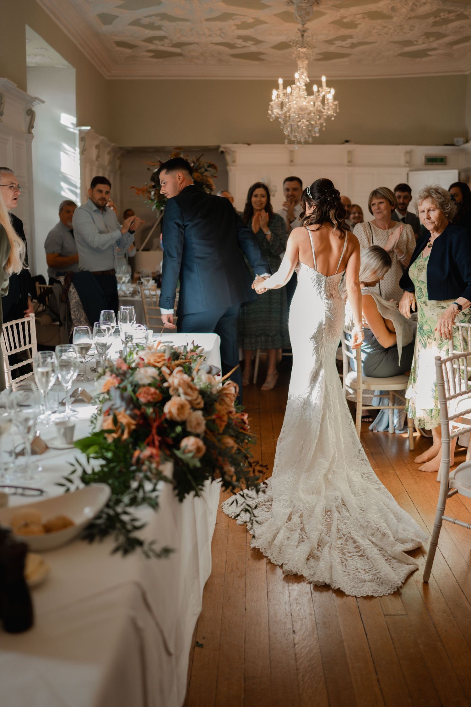 A series of elegant wedding reception photos showing a beautiful venue with crystal chandeliers and white table settings.