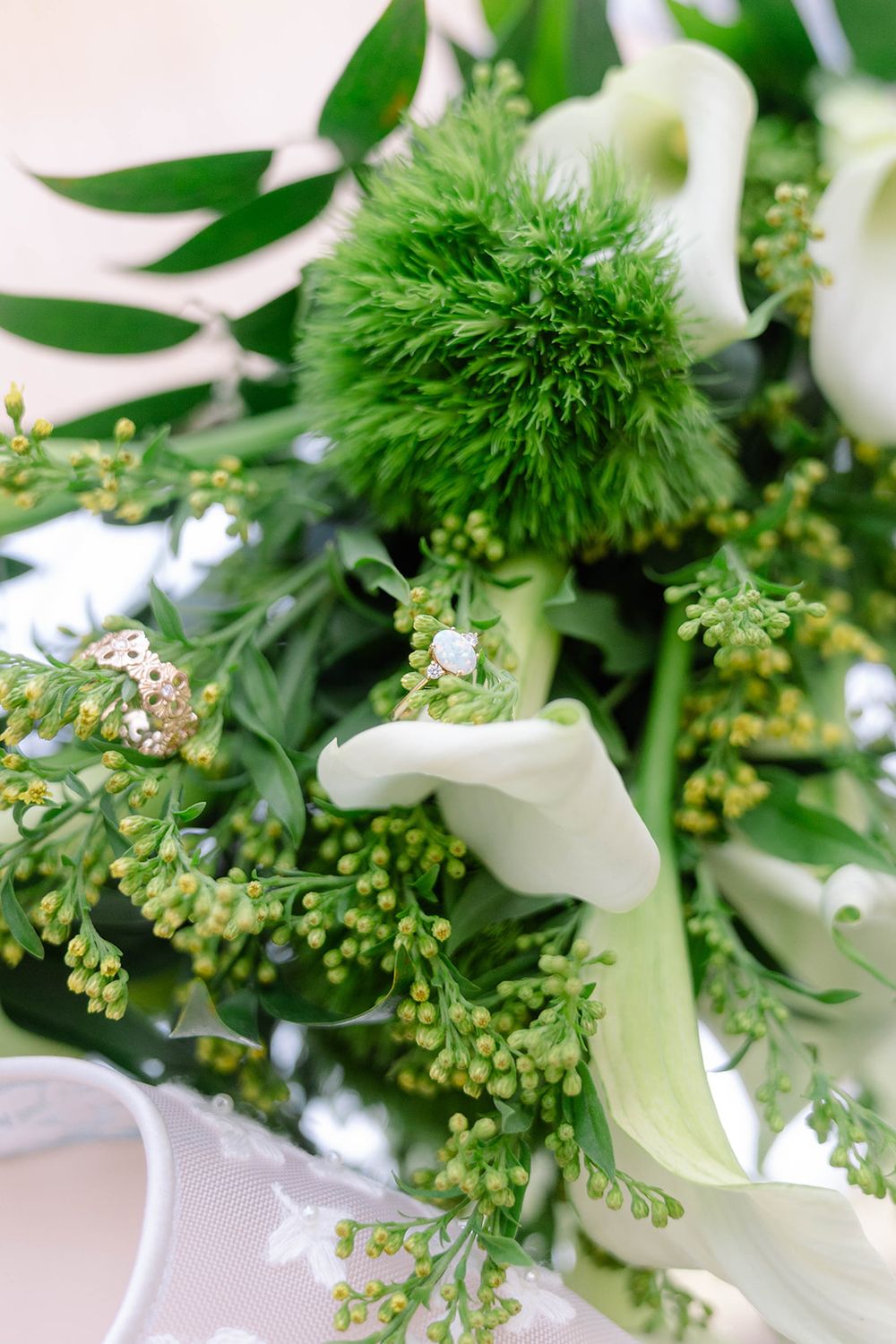 Fresh white calla lilies and green foliage arranged with delicate small buds in an elegant floral display.