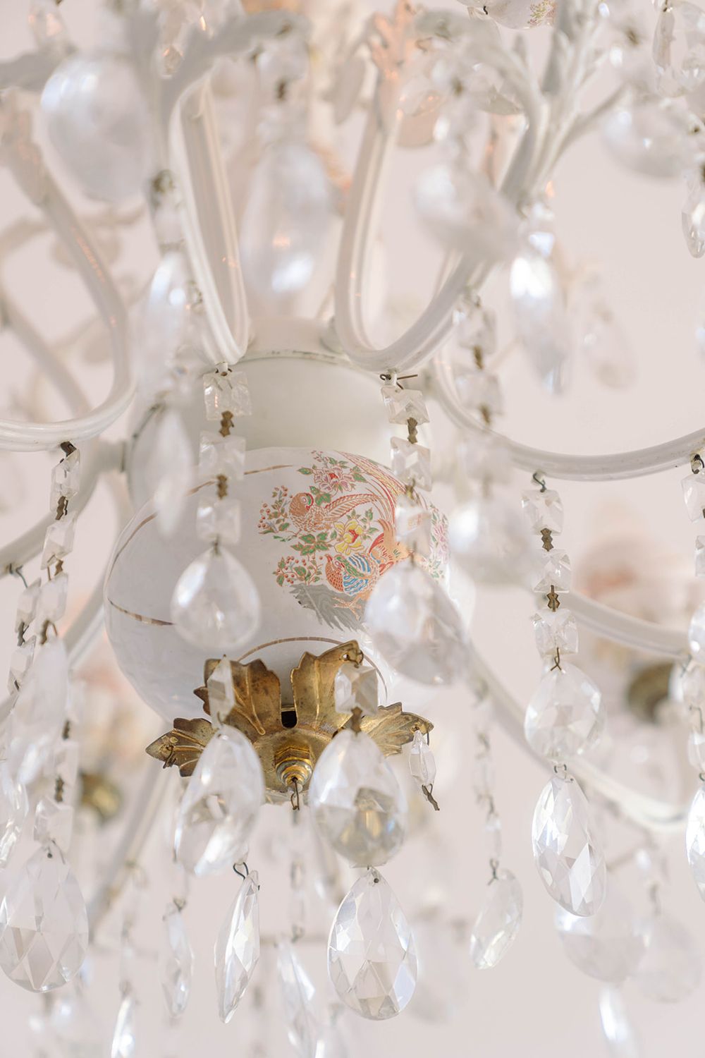 Close-up of an ornate crystal chandelier with vintage floral details and hanging glass drops.