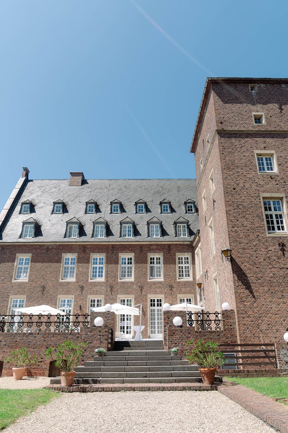 Historic stone mansion with white dormers and grand entrance staircase.