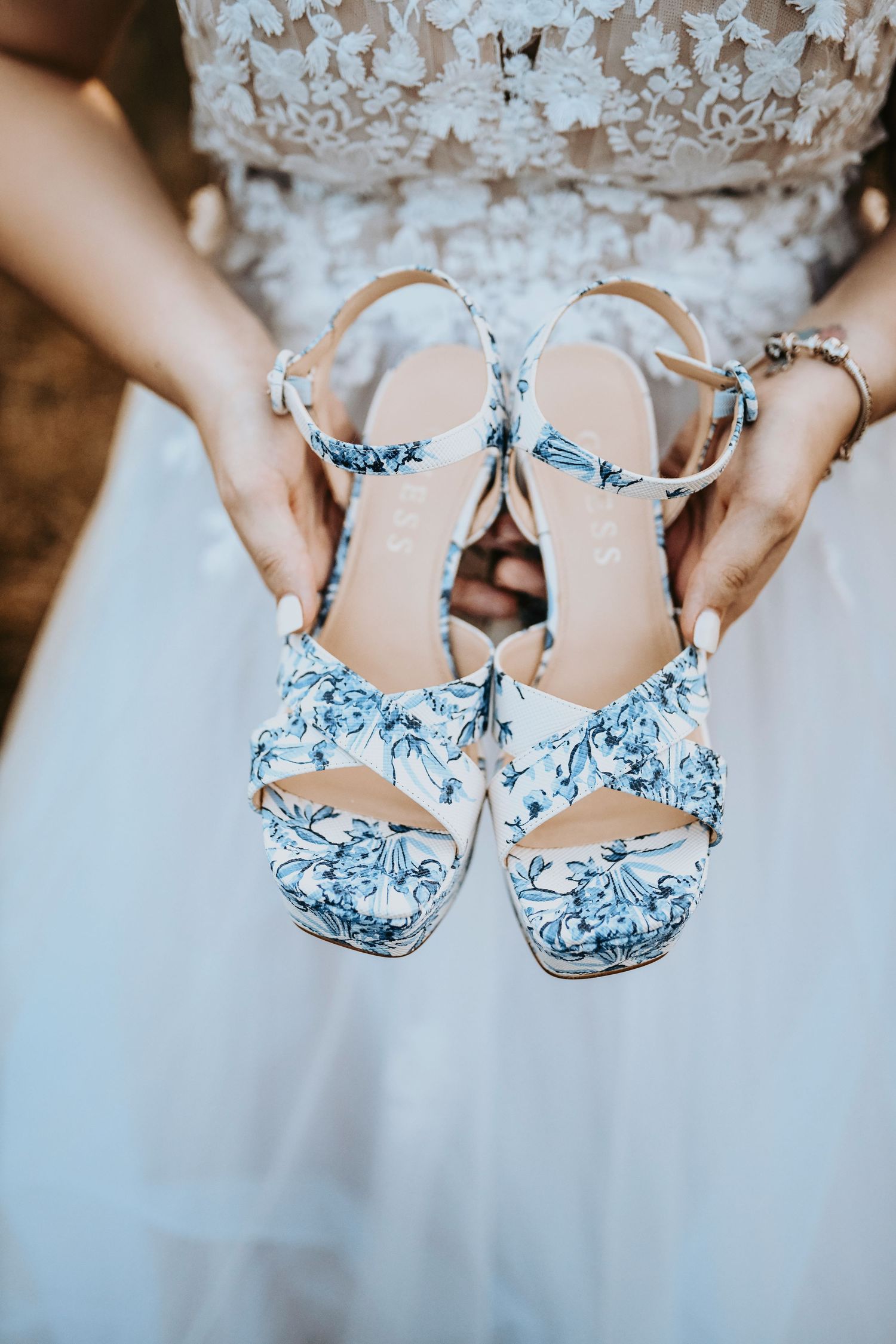 Bride in blue and white vintage heels and embroidered veil standing in Texas hills at golden hour.