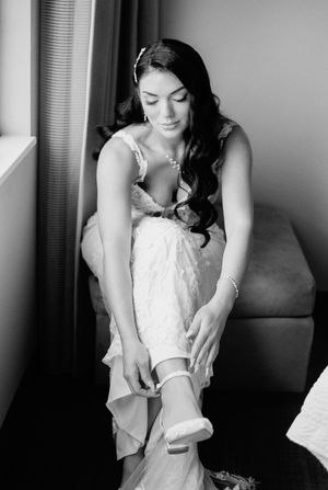 A black and white sequence showing someone adjusting a garter belt on their leg in an intimate getting-ready moment.