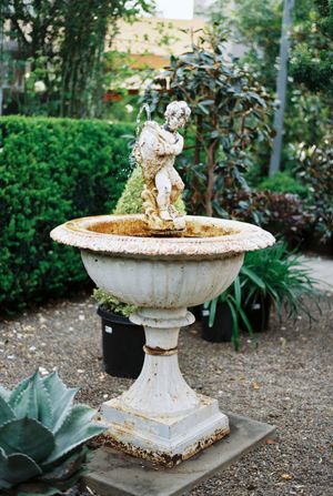 Vintage white stone garden urns arranged on a gravel path with decorative elements.