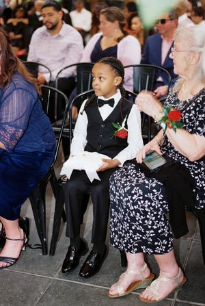 Guests in formal attire sit at a wedding reception showing festive dresses, suits and shoes.