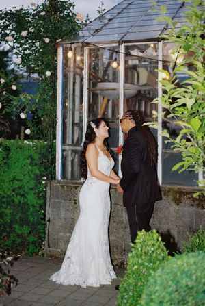 A couple share their first dance outdoors on a garden patio during their evening wedding reception.