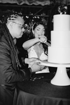 Black and white photo of multiple people blowing out candles on tall wedding cakes.