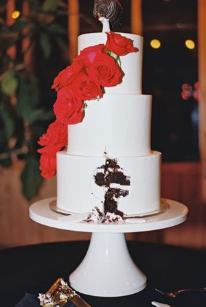 White tiered wedding cake decorated with red roses shown in progressive stages of being cut.