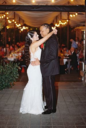 Wedding couple shares romantic first dance under twinkling lights at evening reception.