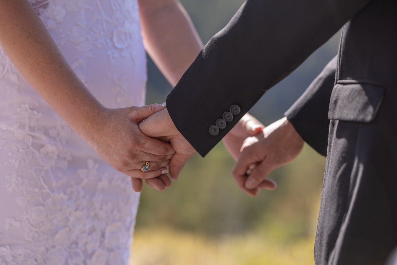 Delicate hands hold each other against a soft focus background creating a tender moment of connection.