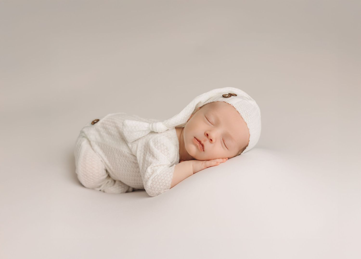 Overhead view of sleeping newborn wrapped in deep purple fabric on matching textured blanket.