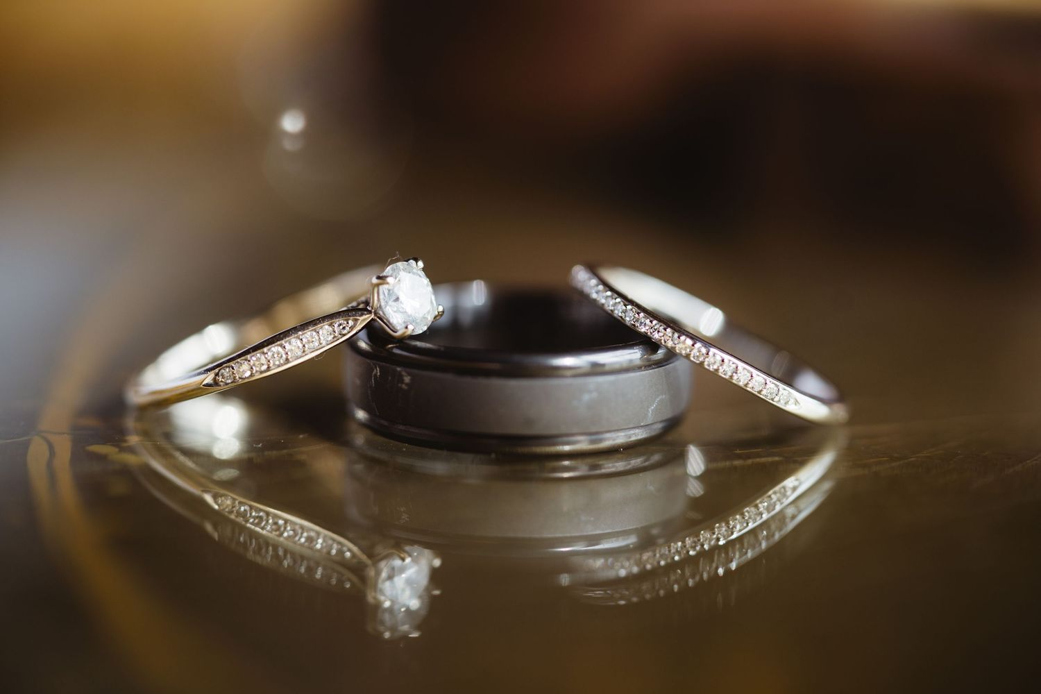 Diamond engagement ring illuminated by reflections on a polished surface with elegant bokeh lighting effects.