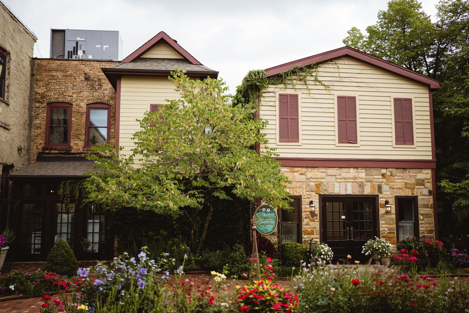 Row of historic houses with colorful gardens and brick facades line a residential street in summer.
