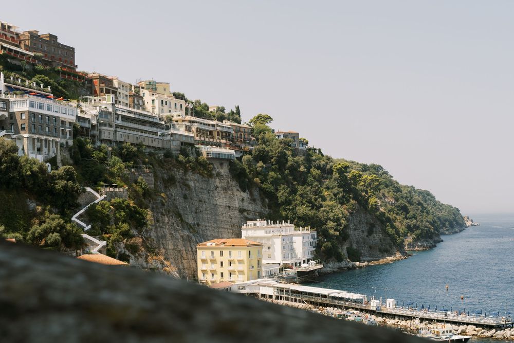 Coastal buildings perch dramatically on rocky cliffs overlooking the Mediterranean Sea along Italy's Amalfi Coast.