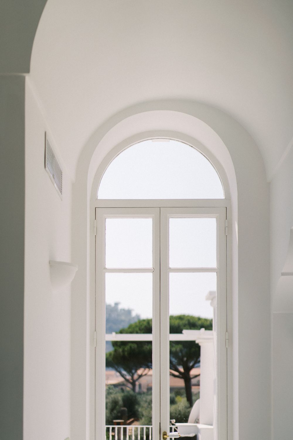 Bright white arched windows and hallway in a modern Mediterranean villa interior.