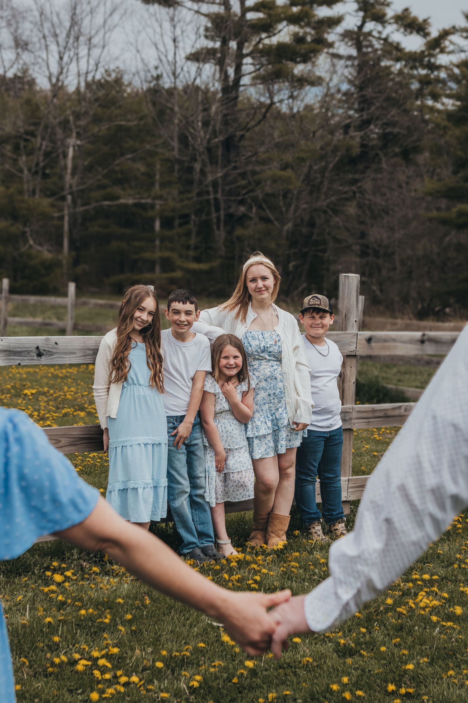 Family group embraces in winter scene with snow-covered trees in background.