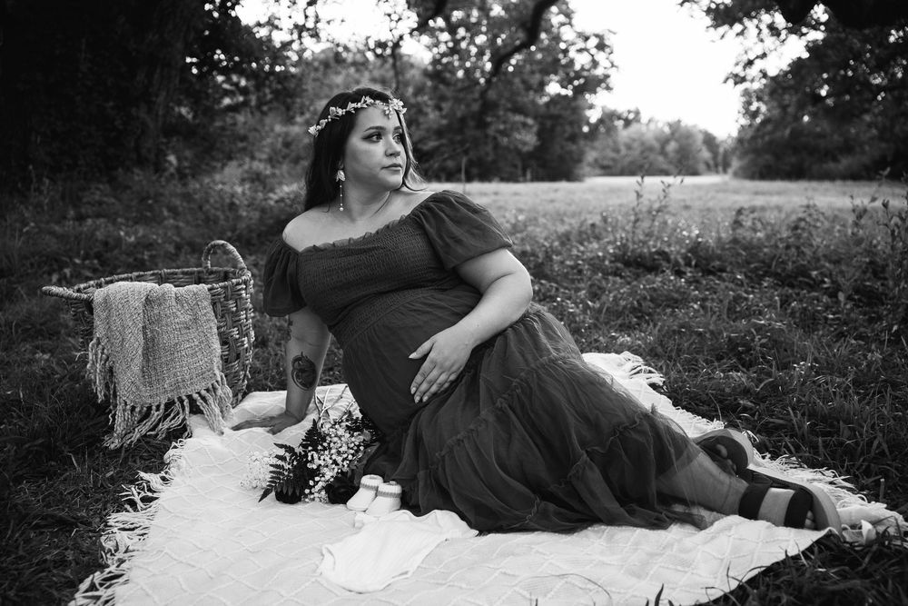 Black and white romantic portraits of couple on picnic blanket outdoors.