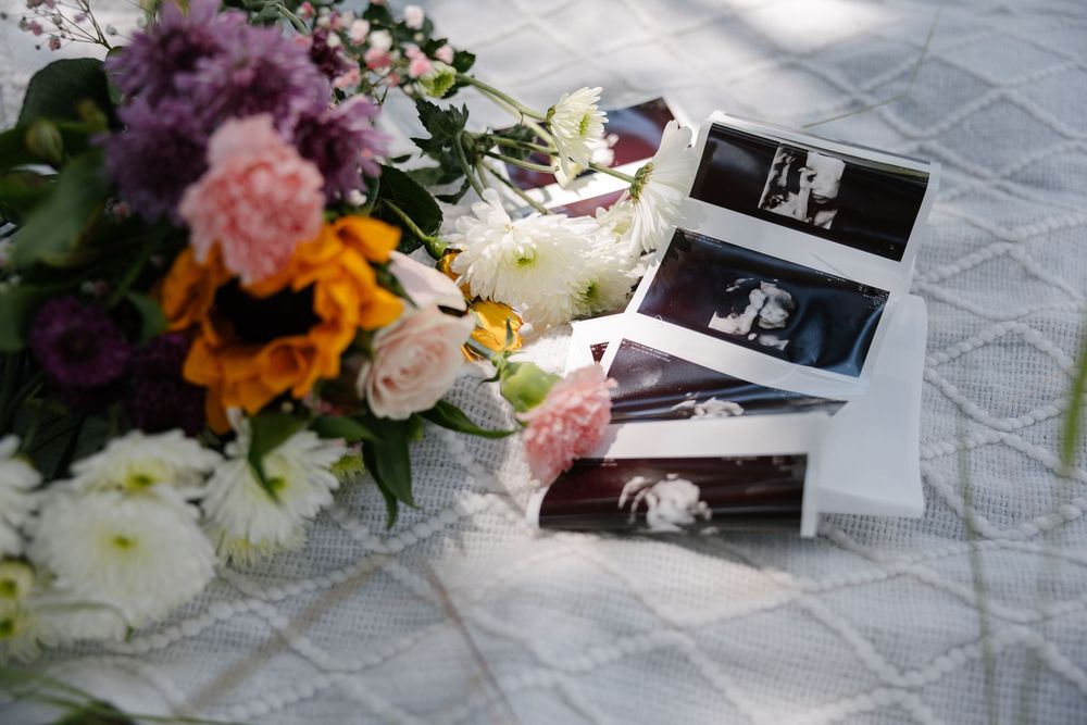 Floral arrangements with pink and purple flowers next to photographs on a textured surface.