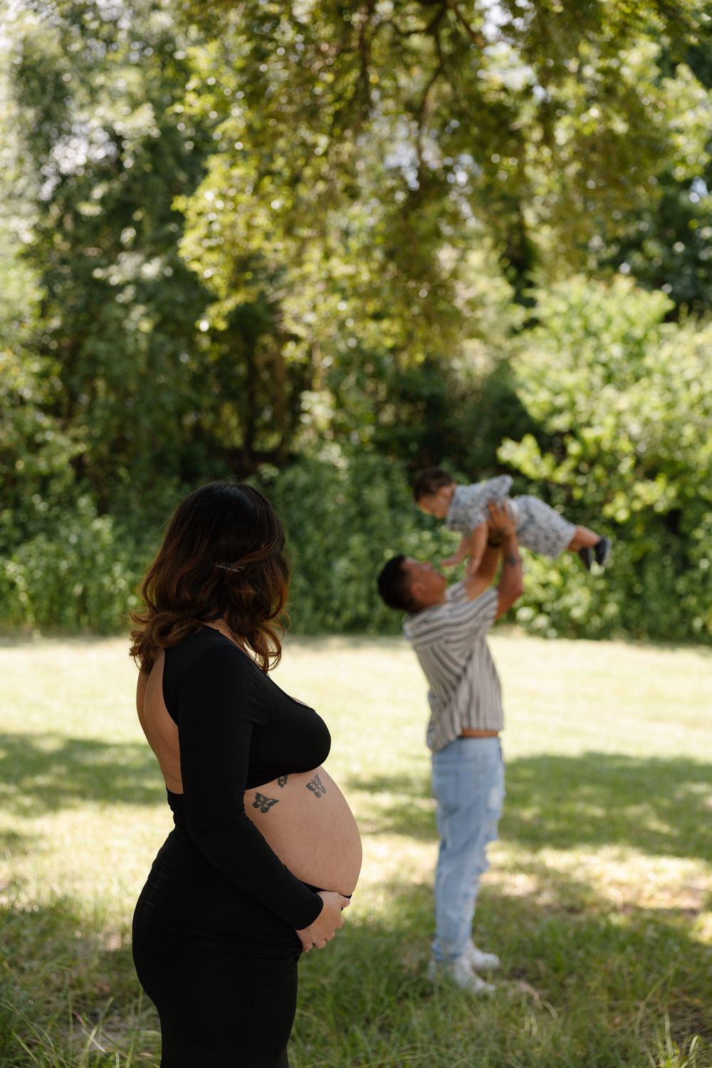 Maternity photography session in a park with natural lighting.