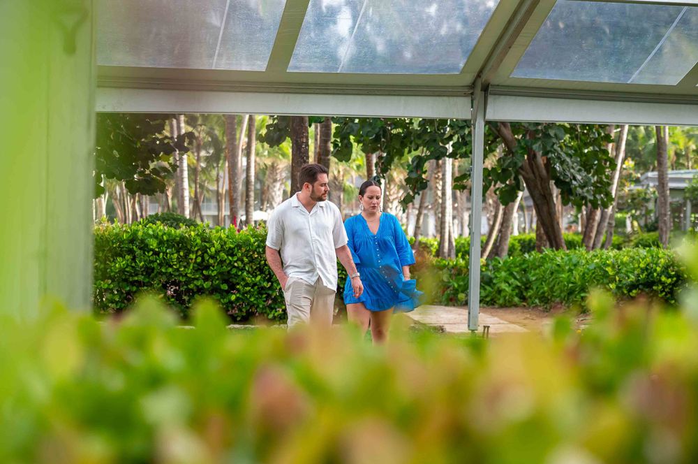 A romantic proposal setup in a covered greenhouse area with floral arrangements and lanterns on the ground.