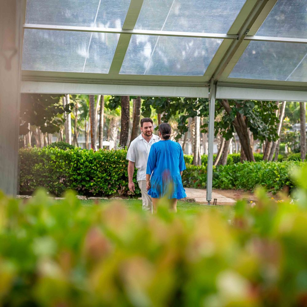 Garden proposal setting with white lanterns and pink floral arrangements under a glass roof structure.