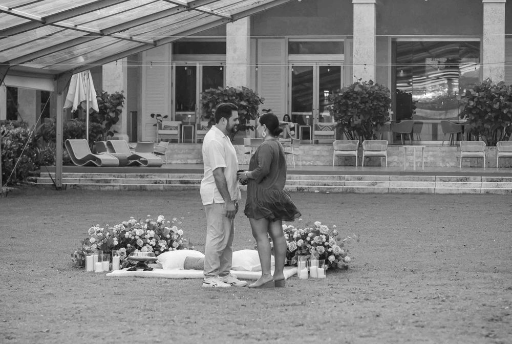 Black and white photo of a proposal moment in a greenhouse with romantic decorations.