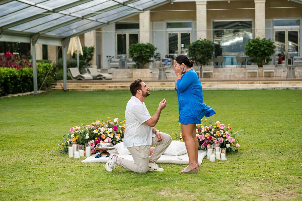 A greenhouse engagement scene with floral arrangements and decorative lighting on the ground.