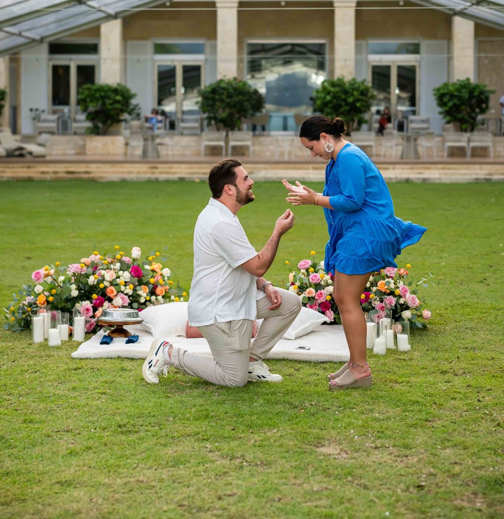 A couple sharing an emotional moment during a marriage proposal surrounded by flowers and candles.