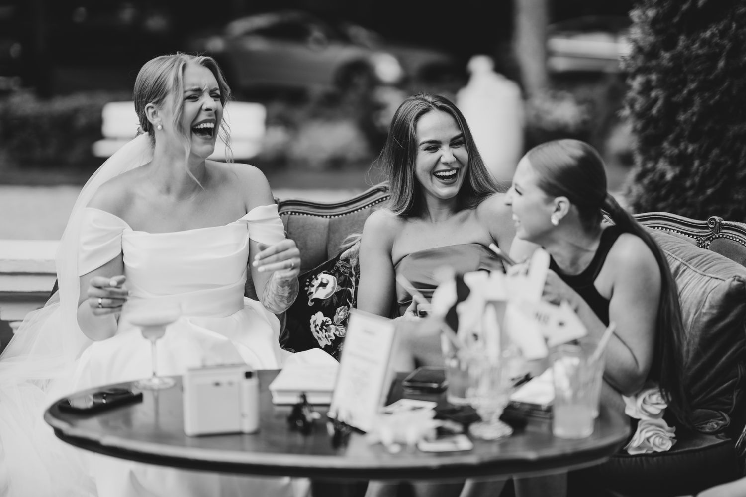 A joyful moment shared between friends at an outdoor wedding reception table.